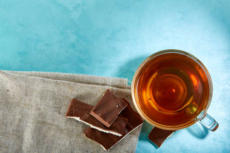 Glass cup of tea and chocolate close-up on blue background.の写真素材