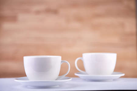 Two white porcelain teacups on wood texture surface show clean and simple design ideas. Selective focusの写真素材