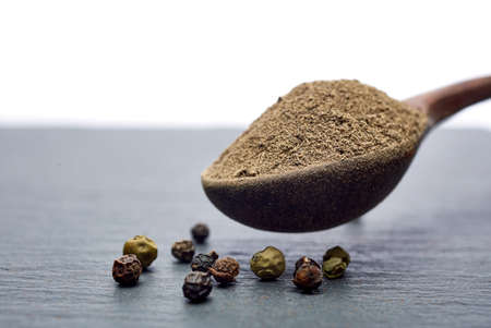 Top view of a wooden spoon full of allspice seeds isolated on dark background, shallow depth of field, front focusの写真素材