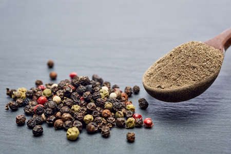 Top view of a wooden spoon full of allspice seeds isolated on dark background, shallow depth of field, front focusの写真素材