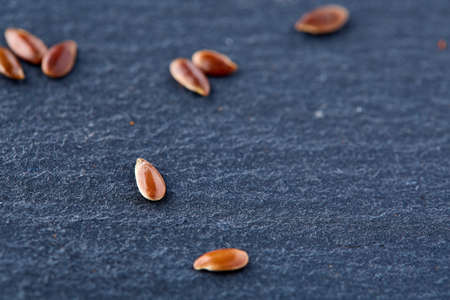 Close up Organic Flax seeds in wooden spoon on black stone plateの写真素材