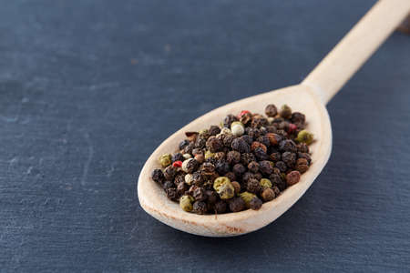 Top view of a wooden spoon full of allspice seeds isolated on dark background, shallow depth of field, front focusの写真素材