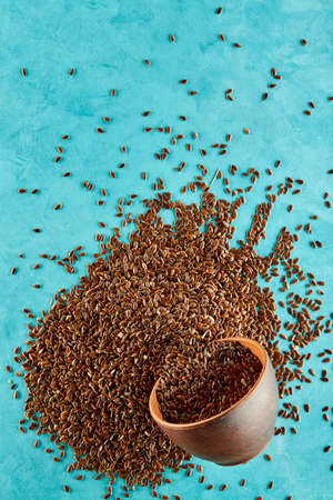 Flax seeds in a clay bowl isolated on blue background, close-up, selective focus, vertical.の写真素材