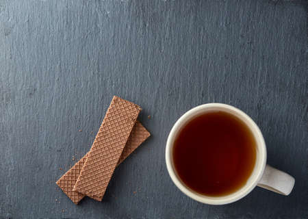 Top view on a cup of tea and cookies isolated on a dark background, close-upの写真素材