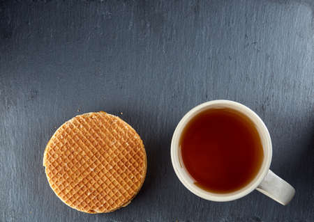 Top view on a cup of tea and cookies isolated on a dark background, close-upの写真素材