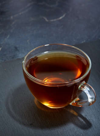 Glass cup of tea isolated on dark marble background, close-upの写真素材