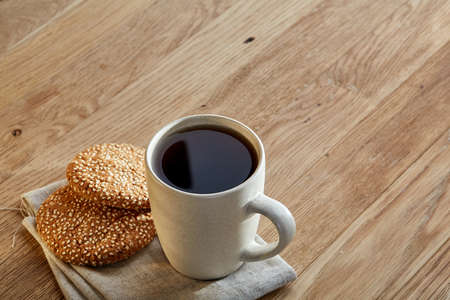 White porcelain cup of earl grey or black tea with cookies decorated with light cotton napkin on a rustic wooden background, top view, selective focusの写真素材