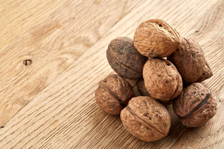 A stack of hard shells of walnuts piled together on light grey fabric cotton napkin and isolated on rustic wooden background, copy space, shallow depth of field, selective focus, front focus, macro. Nutritious food. Healthy lifestyle concept.の写真素材