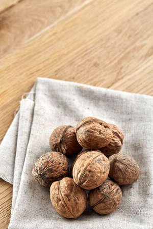 A stack of hard shells of walnuts piled together on light grey fabric cotton napkin and isolated on...