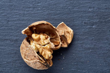 Top view close-up picture of nutritious tasty dry cracked walnuts on dark background, shallow depth of field, selective focus, macro. Seasonal nuts. Oilrich food. Healthy lifestyle concept.の写真素材