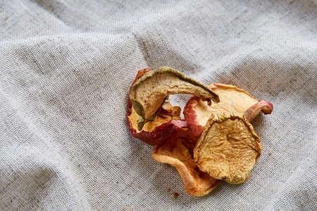 Top view close-up picture of dried apples on light grey cotton tablecloth, copy space, selective...