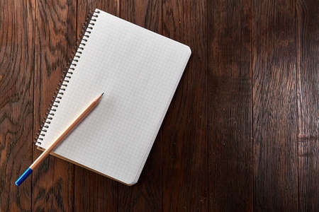 White checked copybook with pencil on pine brown wooden board education conceptの写真素材