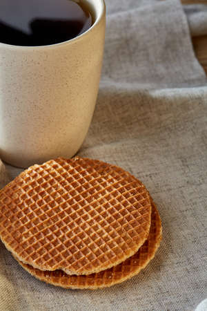 White porcelain cup of earl grey or black tea with wafflesdecorated with light cotton napkin on a rustic wooden background, top view, selective focus, vertical.の写真素材