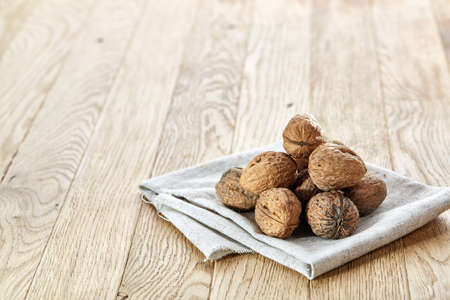 A stack of hard shells of walnuts piled together on light grey fabric cotton napkin and isolated on...