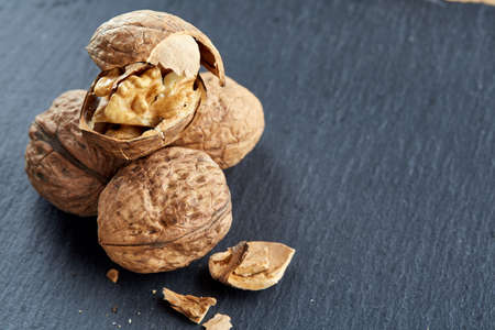 Top view close-up picture of nutritious tasty dry cracked walnuts on dark background, shallow depth...