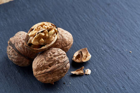 Top view close-up picture of nutritious tasty dry cracked walnuts on dark background, shallow depth of field, selective focus, macro. Seasonal nuts. Oilrich food. Healthy lifestyle concept.の写真素材