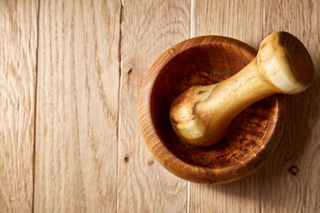 Composition of wooden pestle and mortar arranged on rustic brown wooden background, top view, close-up, shallow depth of field, selective focus, front focus. Kitchen utensils are ready to use.の写真素材