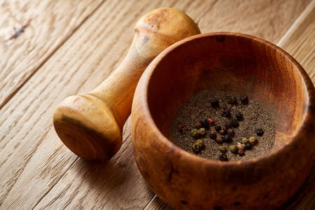 Composition of wooden pestle with spicies and mortar arranged on rustic brown wooden background, ready for grinding, top view, close-up, shallow depth of field, selective focus, front focus. Kitchen utensils are ready to use.の写真素材