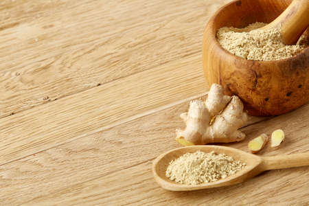 Beautiful kitchen still life wooden mortar full of grind spicies and pestle with ginger and flat kitchen scoop on rustic wooden table, some copy space, close-up, selective focus. Healthy food concept.の写真素材
