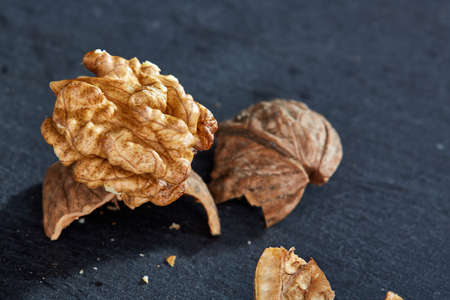 Top view close-up picture of nutritious tasty dry cracked walnuts on dark background, shallow depth...