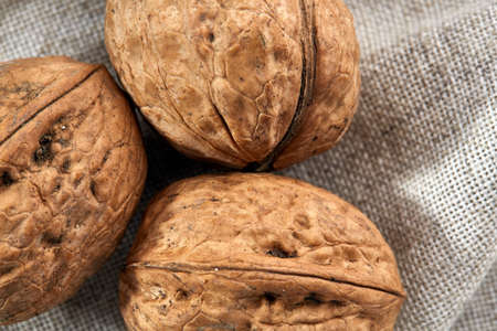 A stack of hard shells of walnuts piled together on light grey fabric cotton tablecloth, copy space,...