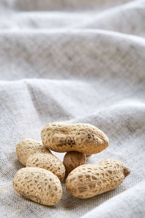 Heap of peanuts on light tablecloth, close-up, shallow depth of field, selective focus, macro