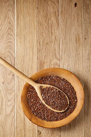 Wooden spoon with flax seeds in a plate on rustic background, top view, close-up, shallow depth of fieldの写真素材