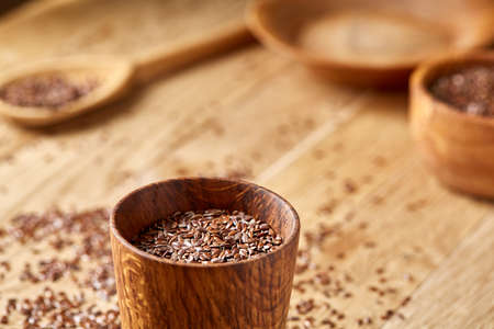 An overturned wooden bowl with linseeds on a rustic background, close-up, shallow depth of field,...