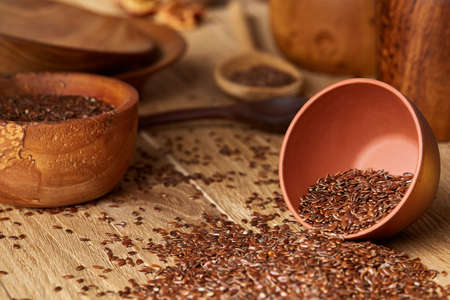 An overturned ceramic bowl with linseeds on a rustic background, close-up, shallow depth of field, selective focusの写真素材