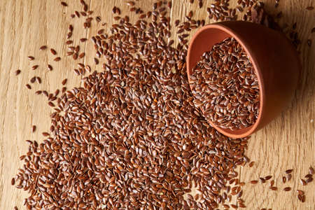 An overturned ceramic bowl with linseeds on a rustic background, close-up, shallow depth of field, selective focusの写真素材