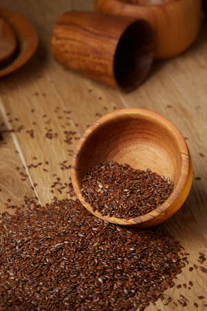 An overturned wooden bowl with linseeds on a rustic background, close-up, shallow depth of field, selective focusの写真素材
