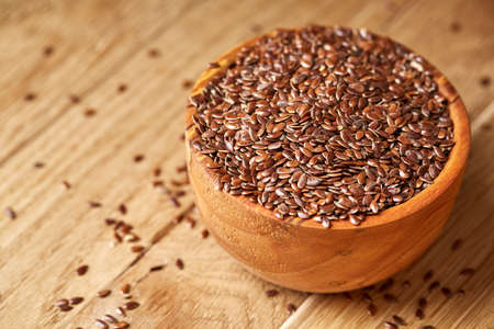 An overturned wooden bowl with linseeds on a rustic background, close-up, shallow depth of field, selective focusの写真素材