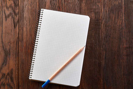 Clean squared copybook with yellow pencil on dark wooden vintage background, top view, education conceptの写真素材