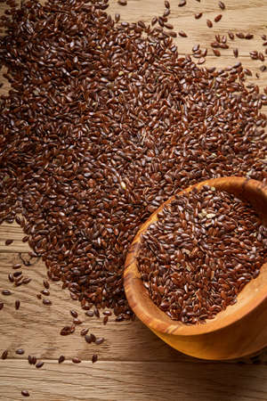 An overturned wooden bowl with linseeds on a rustic background, close-up, shallow depth of field, selective focusの写真素材