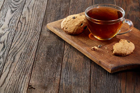 Cup of tea with cookies on a wooden cutting board on vintage background, top viewの写真素材