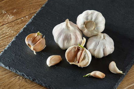 Garlic close up on wooden plate on rustic background, shallow depth of field, selective focus, macro