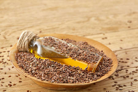 Top view closeup picture flax seeds and linseed oil in a glass bottle on a wooden background, shallow depth of field.の写真素材
