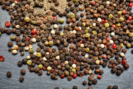 Mix of grind black pepper and black, white, red and yellow peppercorn. Selective focus.