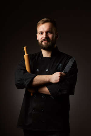 Chef cook holds a knife over dark grey backgroundの写真素材