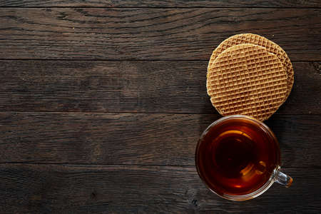 Glass teacup with chocolate chips cookies on cotton napkin on a rustic wooden background, top viewの写真素材