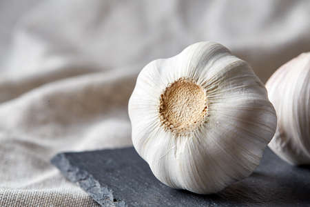 Close up view of two garlic bulbs arranged on a black piece of board, shallow depth of field, selective focus, macroの写真素材
