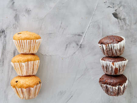 Tasty chocolate muffins arranged in pattern on light textured background, top view, close-up, shallow depth of field, selective focus. Yummy and crunchy dessert. Artistic conceprual pattern. Sweet decoration. Delicious snack. Breakfast background.の写真素材