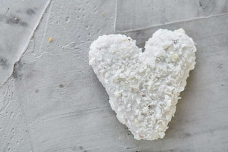 Sweet crunchy coconat heart-shaped biscuits arranged in pattern on light textured background, top view, close-up, shallow depth of field, selective focus. Yummy and crunchy dessert. Artistic conceprual pattern. Delicious snack. Breakfast background.の写真素材