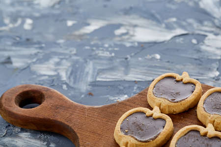 Top view close-up picture of tasty apple-shaped cookies on the cutting board over light abstract background, shallow depth of field, selective focus. Yummy homemade snack. Delicious pastry. Breakfast background.の写真素材