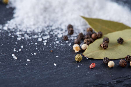 Composition of bay laurel leaf with peppercorn and salt isolated on dark background, top view,...