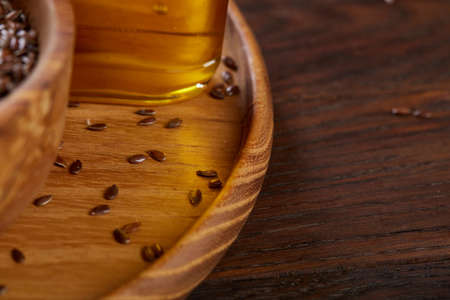 Flax seeds in bowl and flaxseed oil in glass bottle on wooden background, top view, close-up, selective focusの写真素材