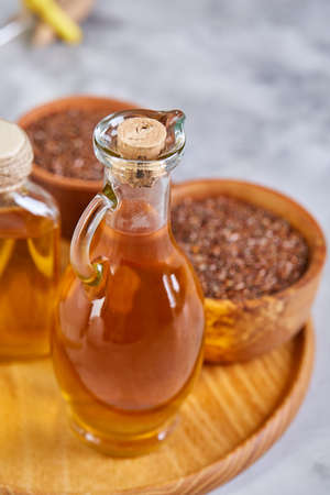 Flax seeds in bowl and flaxseed oil in glass bottle on wooden background, top view, close-up, selective focusの写真素材