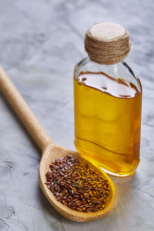 Flax seeds in bowl and flaxseed oil in glass bottle on wooden background, top view, close-up, selective focusの写真素材