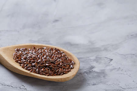 Flax seeds in wooden bowl and spoon on rustic wooden background, top view, shallow depth of fieldの写真素材
