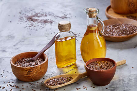 Flax seeds in bowl and flaxseed oil in glass bottle on wooden background, top view, close-up, selective focusの写真素材